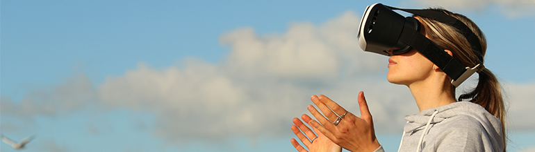 woman outside using a virtual reality headset blue skies