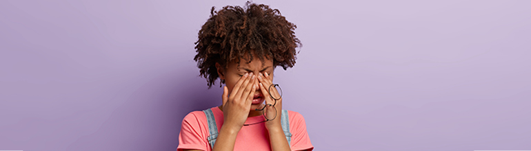 woman rubbing eyes tired glasses in hand