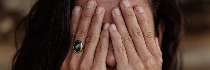 woman covering her eyes with both hands