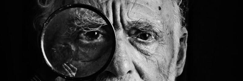 Older man looking through a magnifying glass