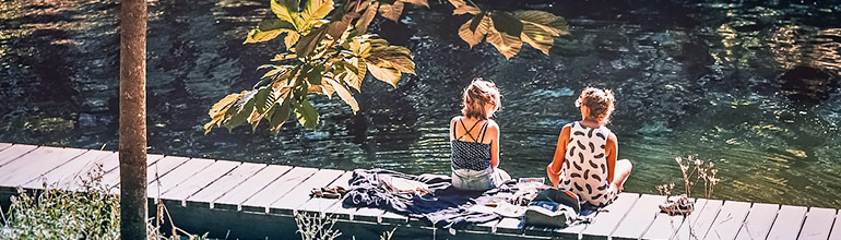 women_sitting_by_lake_summer