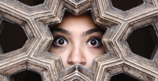 Woman looking through patterned wall