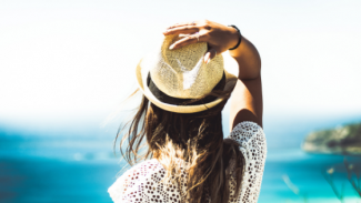 woman wearing sun hat, facing the ocean