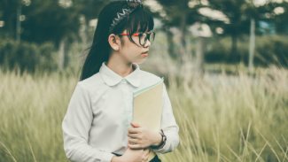 Young girl holding school books in a field