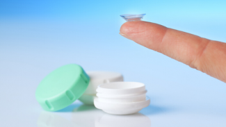 finger balancing contact lens over a lens case