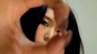 Woman looking through circle formed by fingers