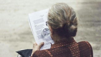 Elder woman viewed from behind, reading a poem through signifying glass