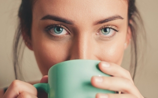 Girl with green eyes drinking from matching green mug