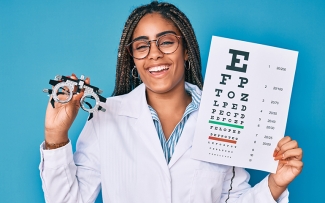 female optician with eye test chart smiling