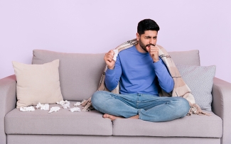 Man sitting on couch feeling sick with a cold or flu