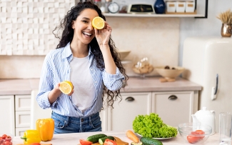 woman smiling with a lemon over her eye for healthy lifestyle