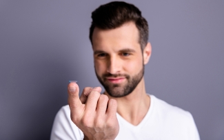 man with contact lens on fingertip