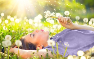 woman in purple shirt with dandelions during the spring