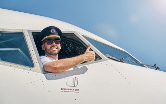 Pilot giving the thumbs up sign outside airplane window