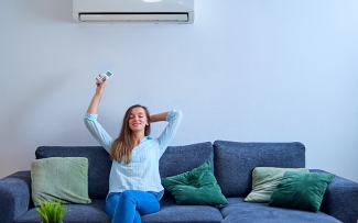 woman sitting on couch turning on air conditioner