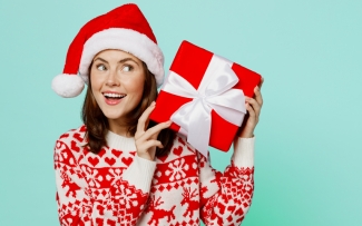 woman holding christmas present up on teal background