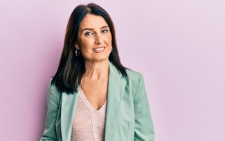 middle aged woman smiling on a light purple background