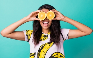 woman smiling with oranges over her eye for healthy lifestyle