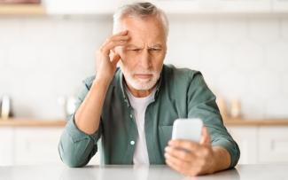 older man having trouble reading phone