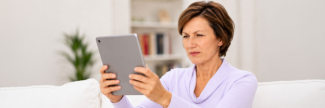 Woman holding tablet at arm's length, squinting to read the screen