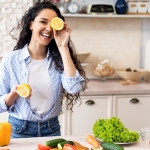 woman smiling with a lemon over her eye for healthy lifestyle