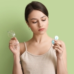 woman holding lenses and glasses making a decision