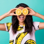 woman smiling with oranges over her eye for healthy lifestyle