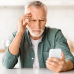 older man having trouble reading phone